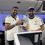 two men standing in an airplane holding trophies