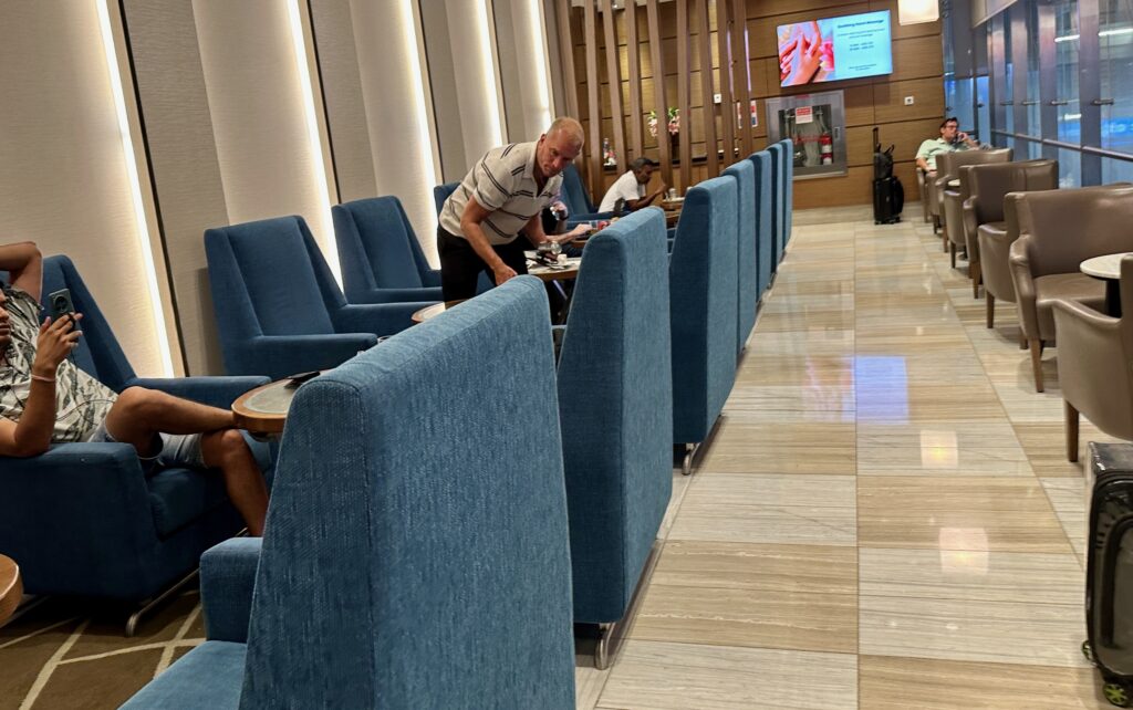 a man standing at a table in a room with blue chairs