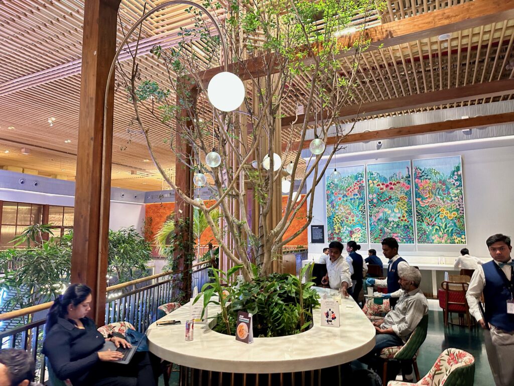 a group of people sitting at a table in a room with a tree