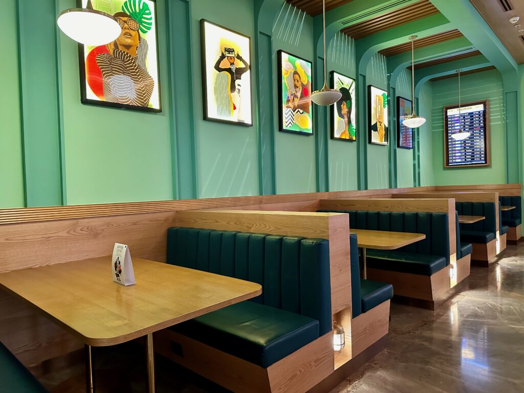 a booth seating with green benches and art on the wall