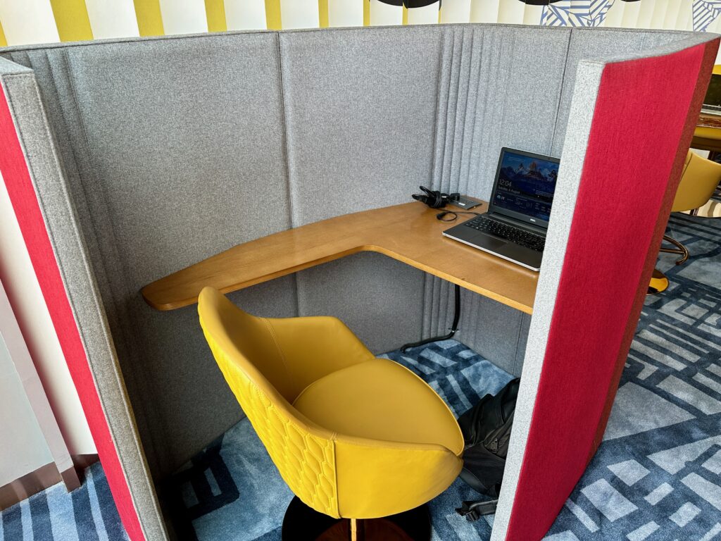 a desk with a laptop and a chair in a booth