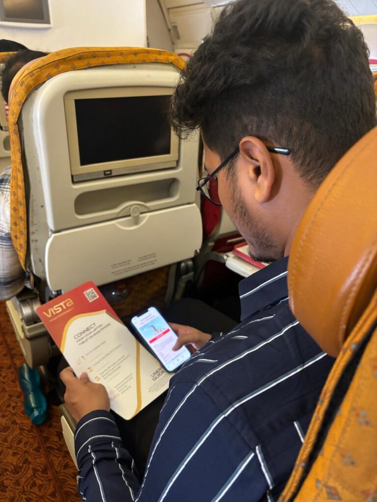 a man sitting in an airplane looking at a cell phone