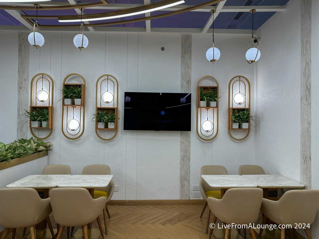 a room with tables and chairs and a television on the wall