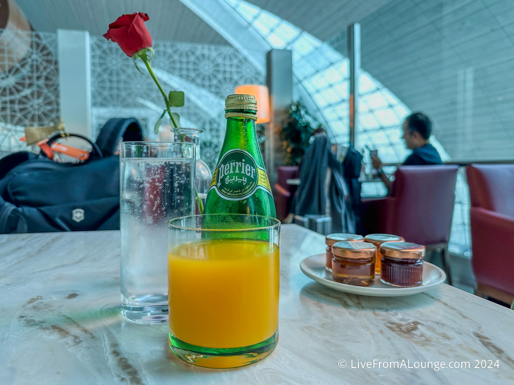 a glass of orange juice and a rose on a table