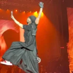 a man in black clothes jumping in the air with his arms up