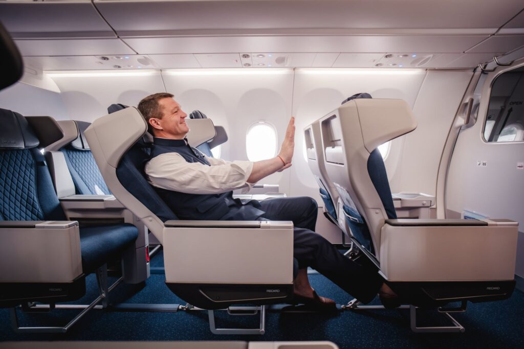 a man sitting in an airplane with his hand up