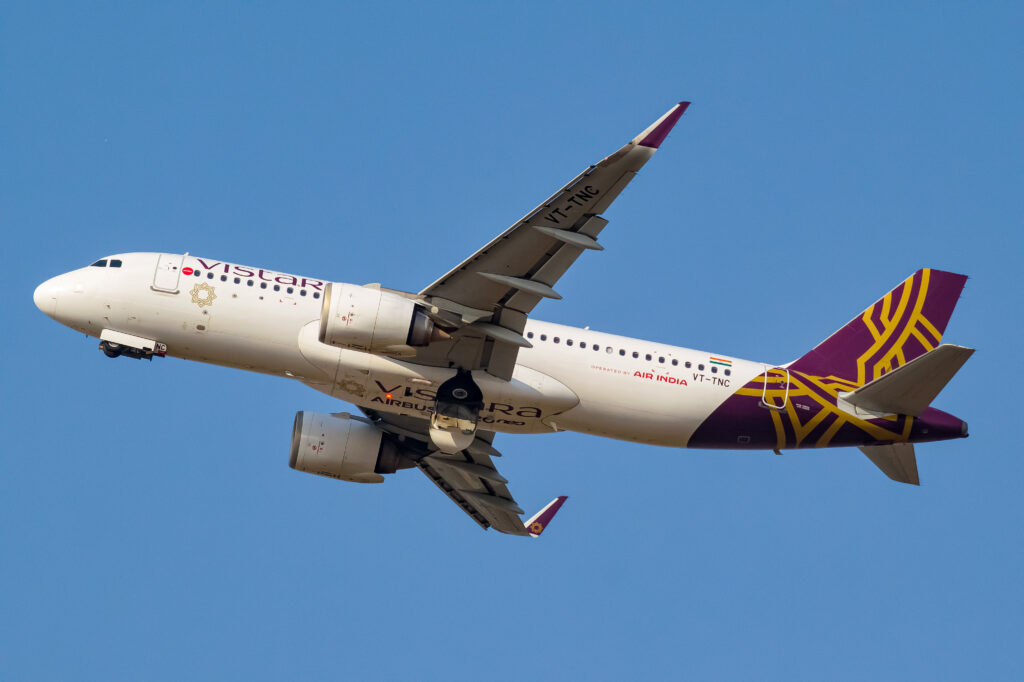 a white and purple airplane flying in the sky