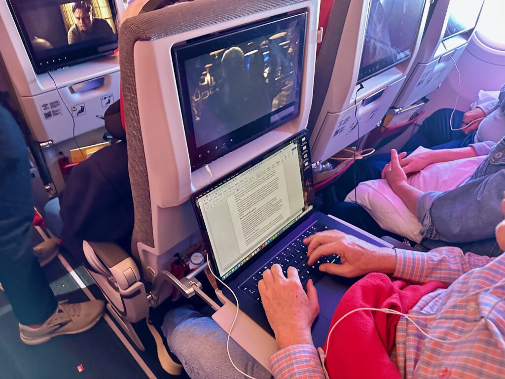 a man sitting in an airplane with a laptop