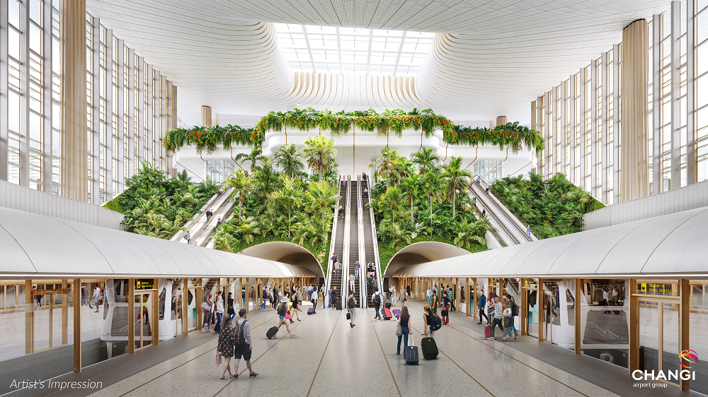 The image is an artist's impression of a modern airport terminal. It features a spacious interior with a high, curved ceiling and large windows allowing natural light to flood the space. In the center, there are escalators flanked by lush greenery, including tall plants and trees, creating a garden-like atmosphere. People are walking and standing with luggage, suggesting a busy, bustling environment. The terminal has a sleek, contemporary design with a focus on integrating nature into the architecture.