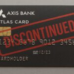 The image shows a black credit card from Axis Bank labeled "Atlas Card." It features a chip and embossed numbers. A large red stamp across the card reads "DISCONTINUED." The card has the word "CARDHOLDER" and a validity date of "12/23."