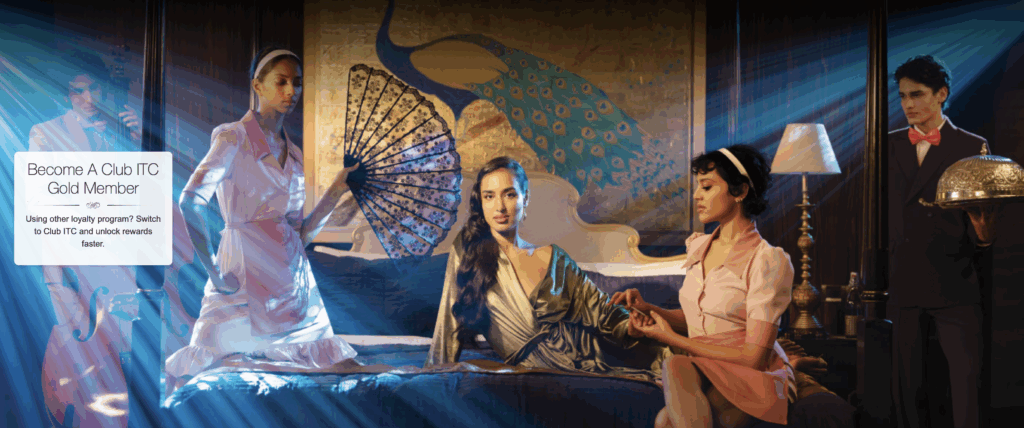 The image features a luxurious setting with four elegantly dressed individuals. A woman in a green dress sits on a bed, holding hands with another woman in a pink outfit. A third woman in a pink dress holds a decorative fan. A man in a suit with a pink bow tie stands to the side, holding a silver tray with a dome cover. The background includes a large peacock mural and a lamp. Text on the left reads, "Become A Club ITC Gold Member. Using other loyalty program? Switch to Club ITC and unlock rewards faster." Blue light rays add a dramatic effect.