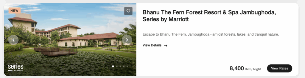 The image shows a promotional display for Bhanu The Fern Forest Resort & Spa Jambughoda, part of the Series by Marriott. It features a scenic view of the resort with a large building surrounded by lush greenery and a pond with lily pads. The sky is clear and blue. On the right, there is text detailing the resort's name, a brief description, and pricing information of 8,400 INR per night. There are buttons for viewing details and rates.