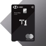 The image shows a black HSBC TravelOne credit card with a chip and contactless symbol. The card features the text "T1" prominently in the center. The Mastercard logo is at the bottom right corner. The background is a gradient of dark gray shades.