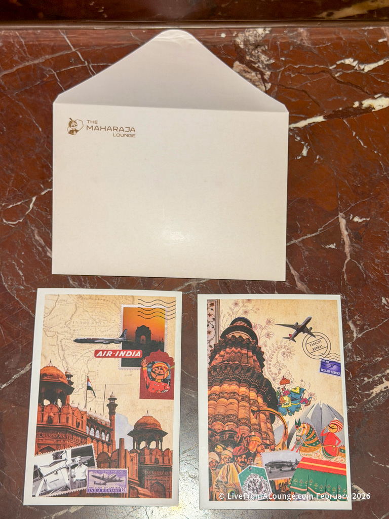 The image shows an open envelope with "The Maharaja Lounge" logo on it, placed on a marbled surface. Below the envelope are two postcards. The left postcard features a collage of Indian landmarks, an Air India airplane, and a cartoon character. The right postcard displays a collage of Indian cultural elements, a temple, and an airplane. Both postcards have a vintage travel theme.