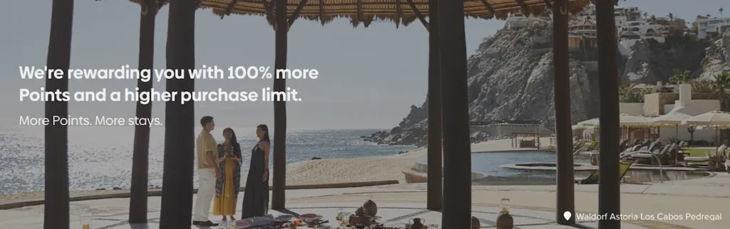 The image shows a scenic view of a coastal resort area with a thatched-roof structure in the foreground. Three people are standing under the structure, looking out towards the ocean. There are lounge chairs and a pool nearby, with rocky cliffs and buildings in the background. Text on the image reads, "We're rewarding you with 100% more Points and a higher purchase limit. More Points. More stays." The location is identified as Waldorf Astoria Los Cabos Pedregal.